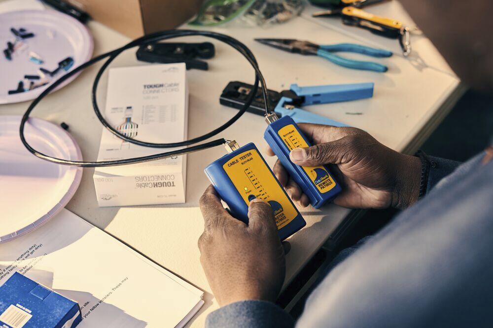 Hands hold two electronic devices connected by a wire