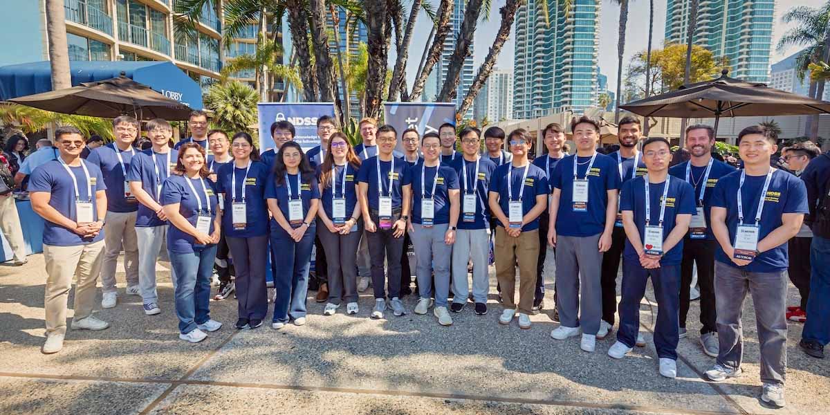 A group of people wearing blue shirts and white lanyards stand outside