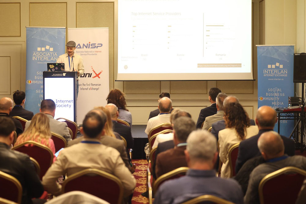 A man stands at a podium and speaks to a seated group